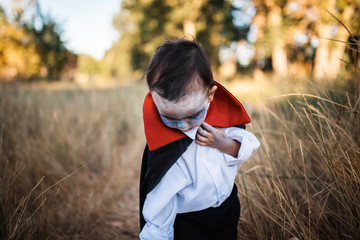 Kid smiling costumed of dracula to halloween on the forest