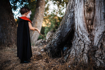 Kid serious costumed of dracula to halloween on the forest
