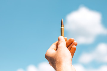 bullet in hand closeup against blue sky