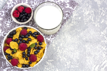 Healthy tasty breakfast: bowl with corn flakes and berries and glass of milk.