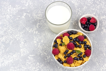 Healthy tasty breakfast: bowl with corn flakes and berries and glass of milk.