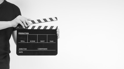 Naklejka premium A man is standing with hands is holding black Clapperboard or movie slate. it use in video production ,film, cinema industry.It is white background.