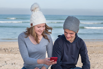 Happy male and female models wearing knitted beanies with Bluetooth speakers inside, listening to...