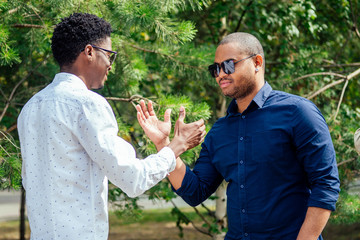 two stylish young friends hugging long-awaited meeting in street parking