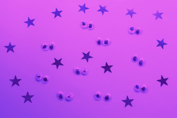 Decorative eyes on a lilac background in neon light. Halloween trick or treat concept. Creative concept for halloween. Flat lay, top view, copy space