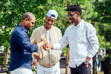 a group of three fashionable well-dressed cool African American guys students communicating on the street