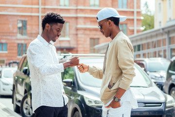 two stylish young friends hugging long-awaited meeting in street parking