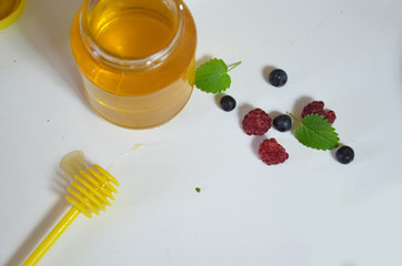 Healthy breakfast ingredients. fresh fruit, berries mint, a jar of honey with a spoon for honey on a white background. Top view, copy space