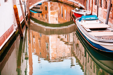 Fototapeta na wymiar Reflection in canal of boat, buildings and bridge in Venice, Italy