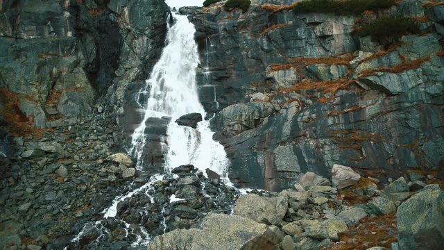 Water falling down by black stones of Skok waterfall, Slovakia. Slow motion footage.