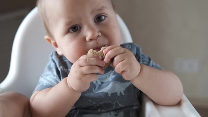 Little baby eating kids homemade cookies himself and smiling. Slow motion
