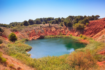 The lake in a old bauxite's red soils quarry cave in Puglia, Otranto, Salento, Italy. The digging was filled with natural waters.