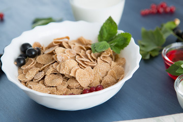Healthy breakfast with cornflakes and fresh berries on white wooden Healthy tasty breakfast multigrain wholewheat healthy cereals with strawberries, raspberries, black currants and red currants.