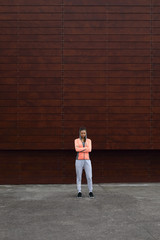 Sporty young woman standing outside with arms crossed. Fitness success and urban workout motivation concept.