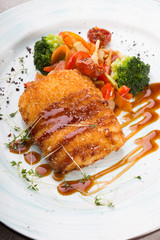 Breaded fish cutlet served with grilled vegetables