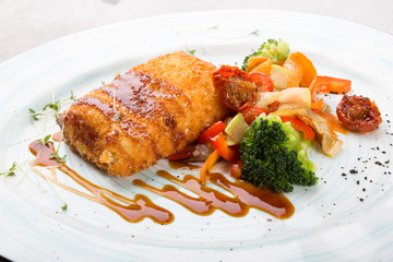 Breaded fish cutlet served with grilled vegetables