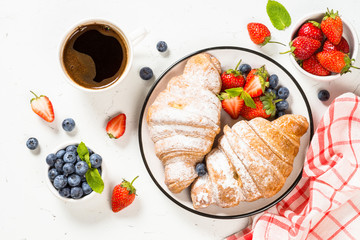 Croissant with fresh berries and cup of coffee.