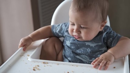 Little baby eating kids homemade cookies himself and smiling. Slow motion