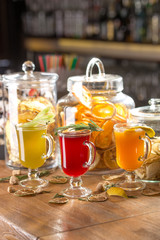 Cups with different hot winter tea with lemon, rosemary and celery on wooden bar counter