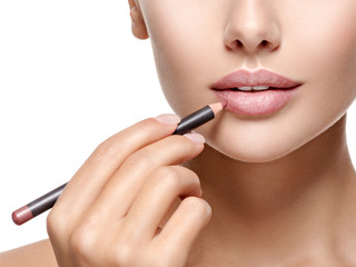 Beautiful woman applying lipstick with cosmetic pencil