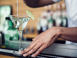 Male bartender stirring cocktail in martini glass