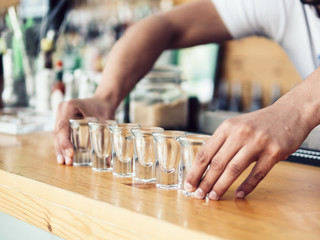 Bartender putting row of shot glasses on counter