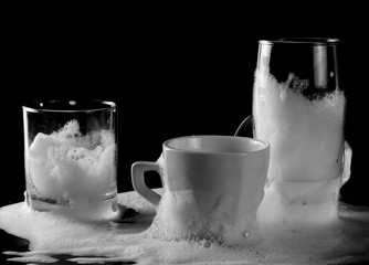 Drinking glass and cleaning, washing foam isolated on black background