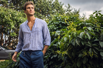 Young handsome man in casual clothes  pose in summer garden.