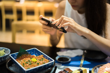 woman photographing food by smartphone