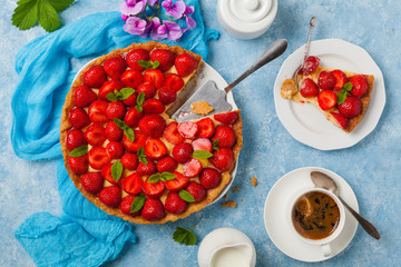 Delicious tart with strawberries on a blue painted background. Top view.