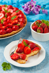 Delicious tart with strawberries on a blue painted background. Front view.