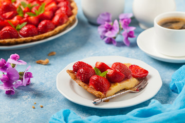 Delicious tart with strawberries on a blue painted background. Front view.
