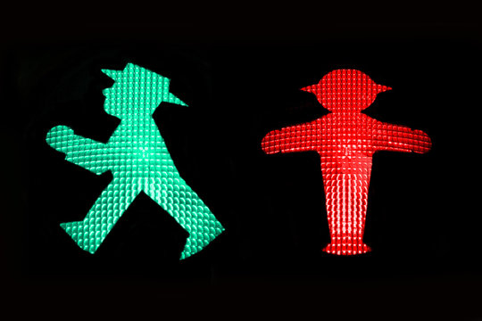 Red and Green pedestrian traffic light with the stop and go icons of the Ampelmann of East Germany isolated on black background, Berlin