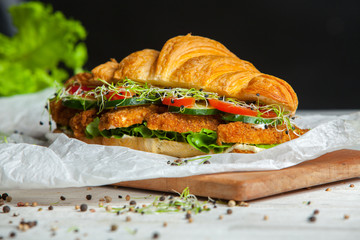 Croissant sandwiches served on wooden board. Croissants with egg, melted cheese, parsley, chicken ham, smoked salmon