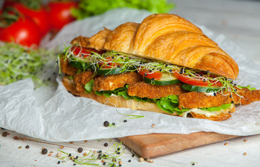 Croissant sandwiches served on wooden board. Croissants with egg, melted cheese, parsley, chicken ham, smoked salmon