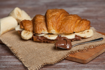 Croissant sandwiches served on wooden board. Croissants with egg, melted cheese, parsley, chicken ham, smoked salmon