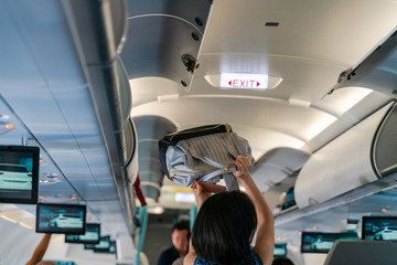Fototapeta premium Hand take off hand luggage. Bag cabin on top shelf in airplane
