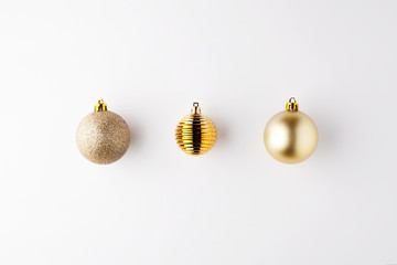 Trendy metallic gold Christmas shiny and matte balls on wite background with copy space