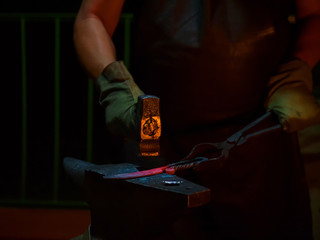 Professional blacksmith working with metal on anvil at forge, workshop. Handmade, craftsmanship and blacksmithing concept