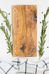 Wooden cutting board, towel, rosemary, pepper on white background. Cooking, recipe concept. Top view, flat lay, mock up, copy space, vertical format