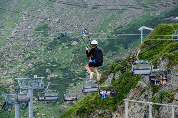 A rider makes a downhill through a chasm through the clouds in the mountains.