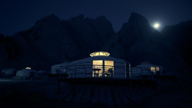 Illuminated Mongolian Gers in dark against rocky mountains - Northern Countryside, Mongolia