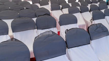 Chairs covered by white and grey cloth.