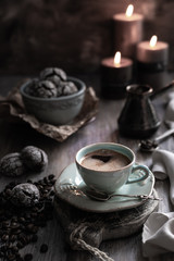 Fototapeta na wymiar Cup of coffee with coffee beans and chocolate biscuit with candles on a beautiful brown background.