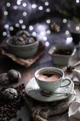 Cup of coffee with coffee beans and chocolate chip cookie with fried New Year lights on a beautiful brown background.