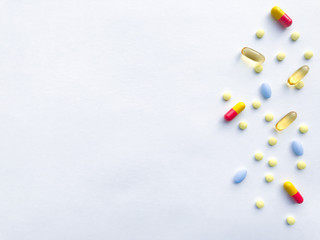 Many colorful pills on the right against a white textured rough paper sheet with place for text