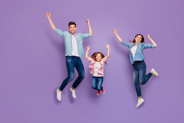 Full length photo of three cheerful jumping high family members wear casual clothes isolated purple...