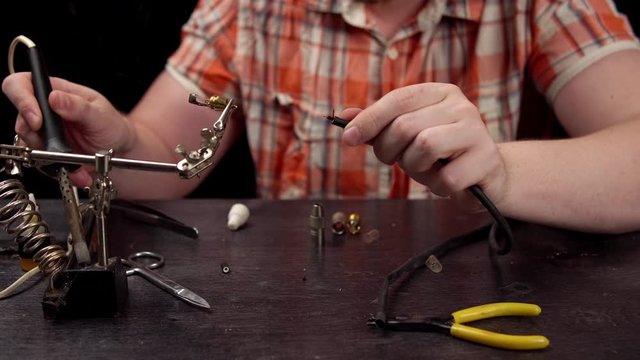 Process of replacing cable for audio cinch connector.Muscled blond electrician solder protects the wire from braid for subsequent soldering to male RCA jack plug.