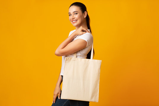 Young Woman Holding White Eco Bag On Yellow Studio Background