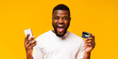 Emotional millennial guy with smartphone and credit card